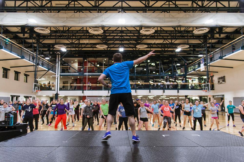 Staff member leading a group of students during a Zumba class